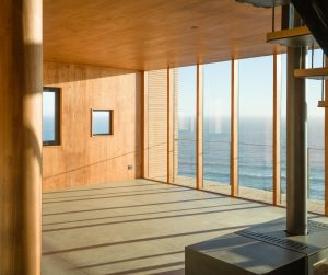 Interior de vivienda costera con cielo y muros revestidos en madera, aplicación arquitectónica de mass timber con vista al océano